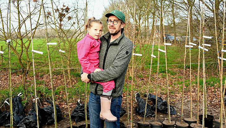 foto van man met kind en jonge bomen op de achtergrond