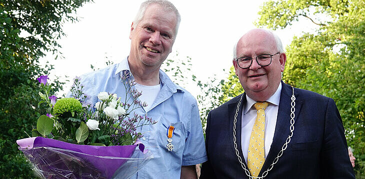 foto van de heer Doornbos (met bos bloemen) en de burgemeester