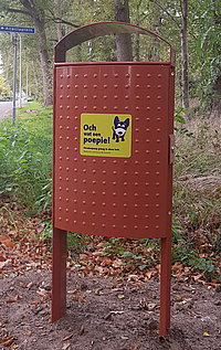 foto van een hondenpoepbak, een rode afvalbak met opvallende sticker
