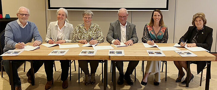 alle deelnemers achter een tafel tijdens de ondertekening
