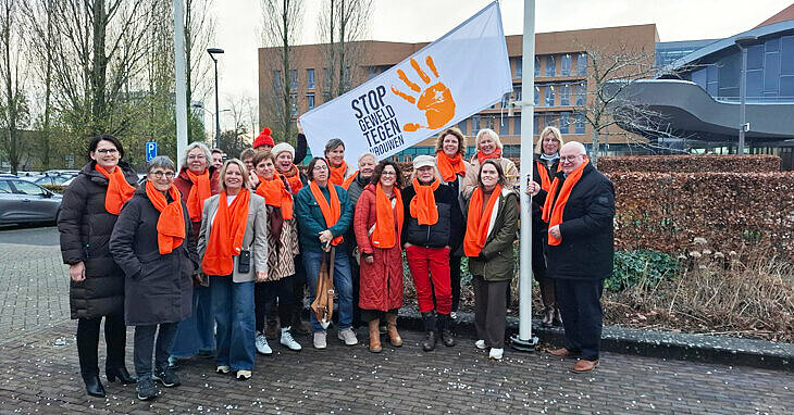 groepsfoto bij de actievlag en iedereen draagt een oranje sjaal